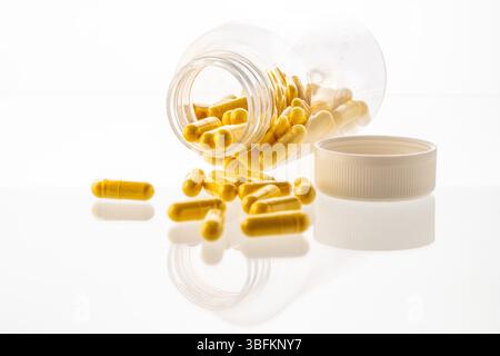 Un vaso con le pillole all'interno giace su uno sfondo bianco. Acido ialuronico, collagene, vitamine o mirtillo per perdere peso. Preparazioni mediche per la salute Foto Stock