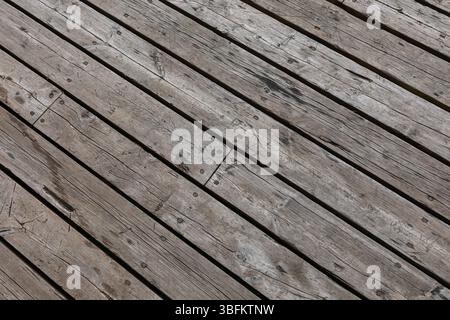 Tavole di legno diagonali con chiodi visibili dall'alto verso il basso con una messa a fuoco nitida. Struttura resistente agli agenti atmosferici adatta come sfondo o superficie di design. Foto Stock