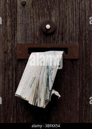 Un vecchio giornale ripieno nella cassetta delle lettere di una vecchia casa abbandonata in un villaggio rurale siciliano spopolato (Sicilia, Italia) Foto Stock