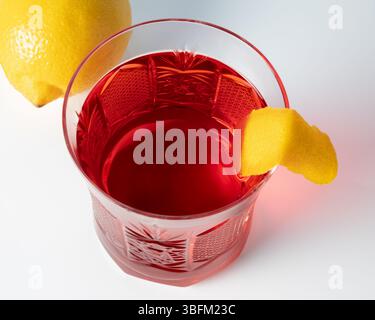 cocktail negroni con torsione al limone e limone intero Foto Stock