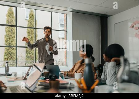 Imprenditore maschile che discute strategie con il team durante una riunione in ufficio Foto Stock