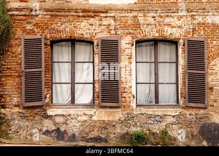 Due telai delle finestre con persiane di riccio su un vecchio edificio in mattoni francesi. Francia. Foto Stock