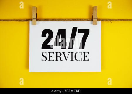 Testo del servizio di assistenza 24 ore e 7 giorni su carta su sfondo giallo Foto Stock