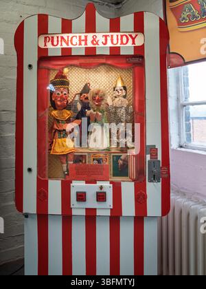 Ellesmere Port, Cheshire, Regno Unito, 05-31-2025: Sala giochi retro Punch e Judy con burattini vivaci all'interno di un involucro a righe. Foto Stock