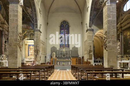 Vista interna di Santa Maria maggiore a Firenze, Italia, con navata, pali in legno, cappelle affrescate, e finestre gotiche in vetro colorato. Foto Stock