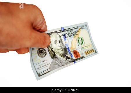 Un'immagine ravvicinata di una mano con una banconota da 100 dollari, che rappresenta transazioni finanziarie, scambi economici e il potere del contante nella finanza personale e aziendale. Foto Stock