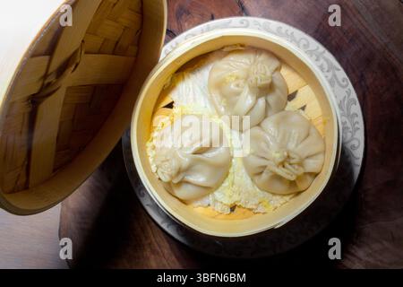 Una vaporiera di bambù contiene tre gnocchi di zuppa su un letto di cavolo, pronti per essere consumati. Foto Stock