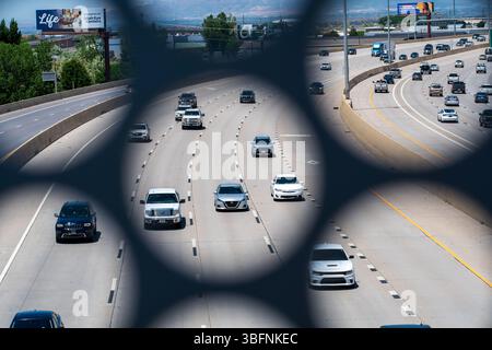 Orem, Utah - 2 giugno 2025: Il traffico in direzione nord si sposta lungo l'Interstate 15 come visto attraverso un'apertura strutturale nel ponte pedonale UVU a Orem, Utah. Foto Stock