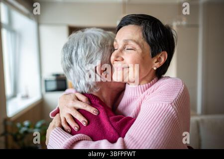 Una coppia di anziani felice che si abbraccia calorosamente. Moglie gioiosa che abbraccia marito, festeggia buone notizie in famiglia Foto Stock