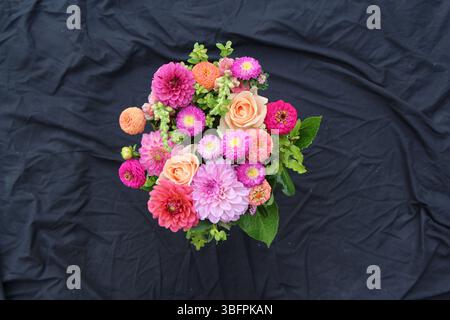 Composizione floreale. La prospettiva guarda in basso direttamente sopra. Un assortimento di colori e tipi di fiori su uno sfondo nero. Foto Stock