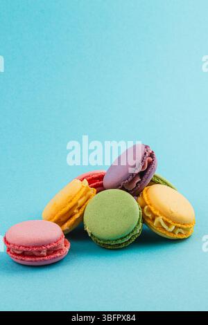 Delizioso assortimento di macaron in vari colori e sapori sono esposti su un vivace sfondo blu, che mostra le loro delicate texture Foto Stock