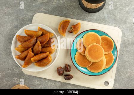 Piatto piatto di dessert arabi assortiti con Qatayef come il pezzo forte, simbolo dei dolci Ramadan e della cucina mediorientale Foto Stock