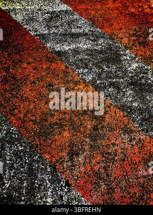 Le linee rosse e nere creano un motivo accattivante su una superficie ruvida, illuminata dalla calda luce del tardo pomeriggio Foto Stock