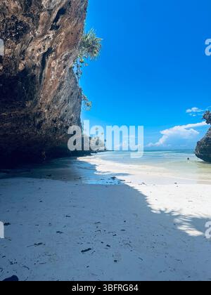 spiaggia sabbiosa circondata da una grande roccia e da un'enorme scogliera Foto Stock