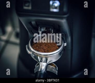 Macchina per il caffè per macinare i chicchi di caffè e versare il caffè macinato in un portafiltro per preparare l'espresso Foto Stock
