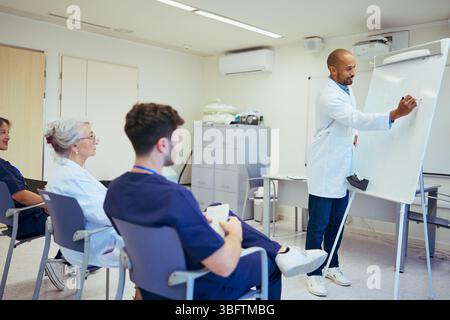 Medico che tiene una lezione al personale medico nella sala riunioni dell'ospedale Foto Stock