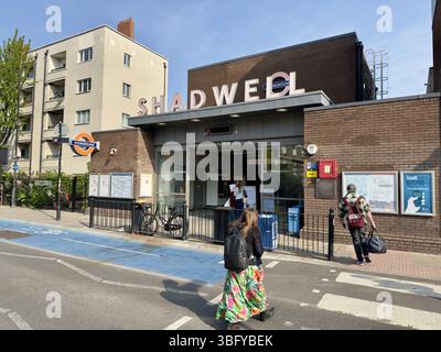 LONDRA, INGHILTERRA – 27 APRILE 2025: Le persone camminano vicino all'ingresso della stazione Shadwell Overground di Londra, Inghilterra. Foto Stock