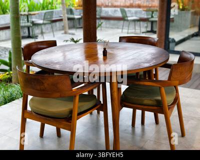 Un tavolo da pranzo rotondo in legno con quattro sedie in legno corrispondenti in un caffè all'aperto Foto Stock