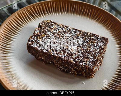 Dessert fatto in casa fetta di cocco al cioccolato crudo su un piatto di ceramica Foto Stock