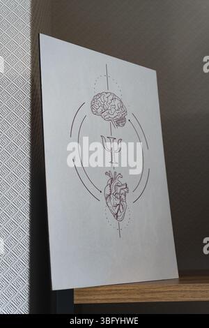 Vista ravvicinata e angolata di una stampa artistica minimalista con un cervello stilizzato, la lettera greca psi (simbolo della psicologia) e un cuore Foto Stock