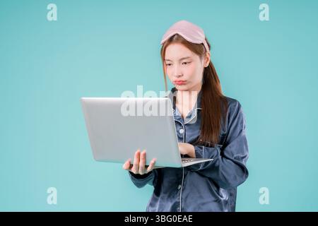 Asiatico che indossa pigiama imprenditore notebook Social Lady che lavora online, Una giovane donna d'affari in Foto Stock
