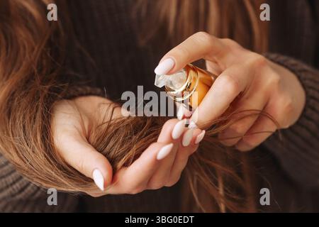 Donna che applica olio ai capelli. Trattamento nutriente per i capelli. Cura naturale dei capelli. Olio cosmetico per mani. Concetto di bellezza dei capelli. Olio organico idratante. Foto Stock