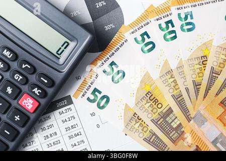 Banconote in euro con calcolatore. Concetto di pianificazione finanziaria. Cinquanta euro di banconote sul foglio di rapporto. Contabilizzazione dei soldi e del budget. Tema bancario ed economico. Foto Stock