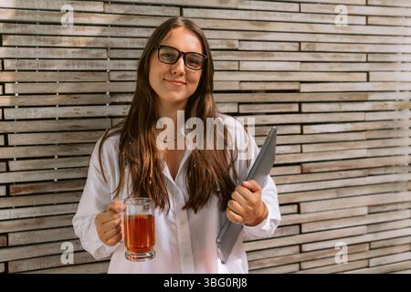 Giovane donna che soggiorna con un portatile e una tazza di tè Foto Stock
