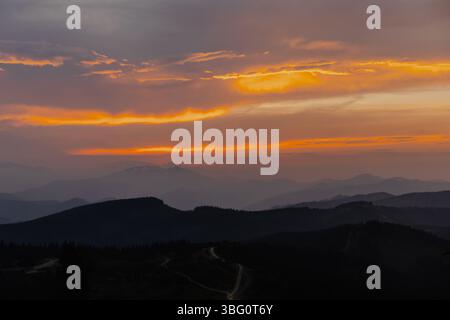 L'ora d'oro dipinge il cielo sopra una vasta catena montuosa, creando uno spettacolo naturale suggestivo e maestoso Foto Stock
