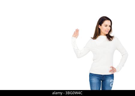 Donna matura che solleva la mano destra verso l'esterno, riposa il braccio sinistro sull'anca in studio fotografico, copia spazio Foto Stock