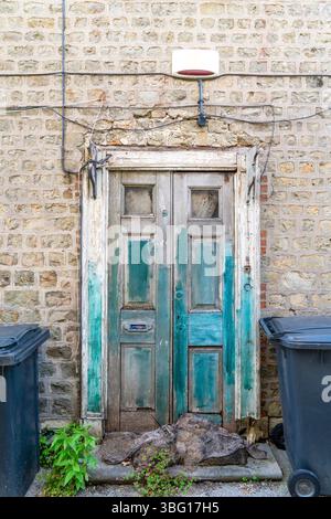 Vecchia porta in legno angosciato con sacchi di sabbia disintegrati sul gradino della porta Foto Stock