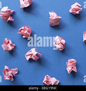 Palline di carta rosa sbriciolati su sfondo blu. Concetto di idea creativa Foto Stock