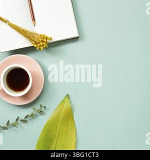 Luogo di lavoro e di studio. Libro di note, tazza di caffè con decorazione floreale. Piano, vista dall'alto, spazio copia Foto Stock