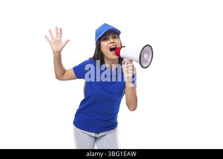 Una giovane promoter molto ben curata con t-shirt e berretto in cotone blu utilizza un altoparlante per annunciare le offerte promozionali Foto Stock