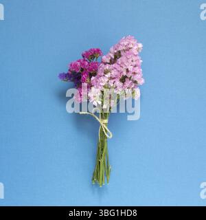 Rosa viola Statice fiori bouquet su sfondo blu. Composizione floreale, piatto, vista dall'alto Foto Stock