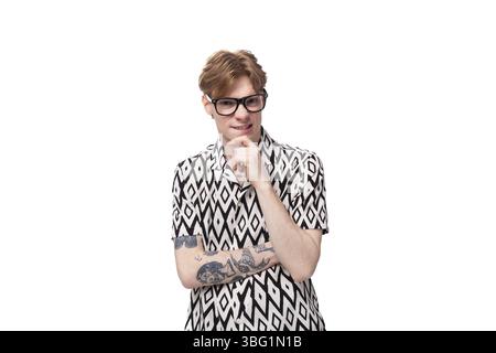 Giovane uomo caucasico dai capelli rossi con occhiali per la visione in una camicia estiva a maniche corte in bianco e nero Foto Stock
