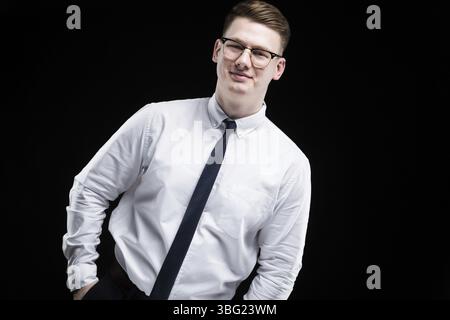 Ritratto di fiducioso bello elegante responsabile imprenditore con le mani nelle tasche su sfondo nero Foto Stock