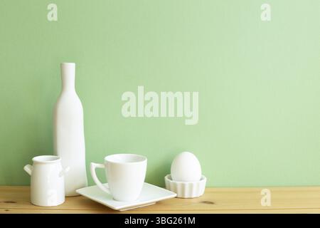 Stoviglie in ceramica bianca su tavolo di legno. Sfondo verde Foto Stock