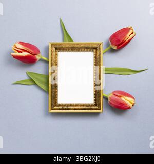 Cornice fotografica vuota con fiori tulipano rossi su sfondo grigio blu. Composizione floreale, piatto, vista dall'alto, spazio per copie Foto Stock
