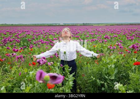 Momenti sereni in un colorato campo di fiori. La donna respira aria fresca con le braccia aperte Foto Stock