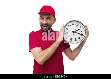 Concetto di consegna rapida in breve, scadenze corriere in uniforme rossa su sfondo bianco con un grande orologio nelle sue mani Foto Stock