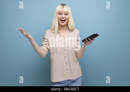 Ritratto di una giovane donna europea abbastanza bionda che guarda lo schermo dello smartphone Foto Stock