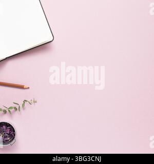 Luogo di lavoro e studio, taccuino vuoto e matita colorata con fiori secchi su sfondo rosa. Piano, vista dall'alto, spazio copia Foto Stock
