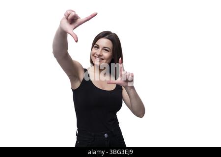 Giovane donna bruna sottile che indossa una T-shirt stretta su sfondo bianco Foto Stock