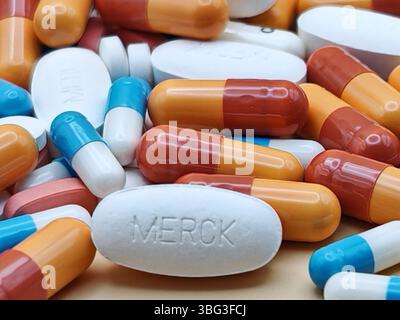 Pillola bianca con impronta MERCK posta su un mucchio di compresse e capsule colorate in una vista farmaceutica. Foto Stock