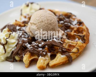 Pancake con gelato e salsa al cioccolato su un piatto bianco Foto Stock