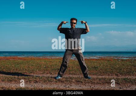 Bell'uomo emozionale che posa sulla riva del lago su sfondo blu Foto Stock