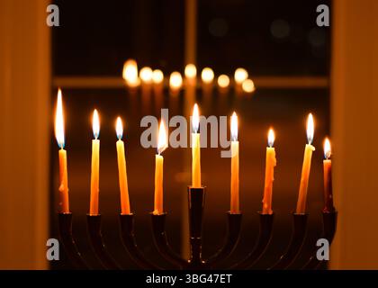 Nove candele Chanukah menorah davanti alla finestra con riflessi di notte Foto Stock