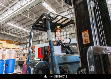 il camionista di carrelli elevatori felice sorridente ama il lavoro del personale. lavoratrici africane nere della fabbrica di merci Foto Stock