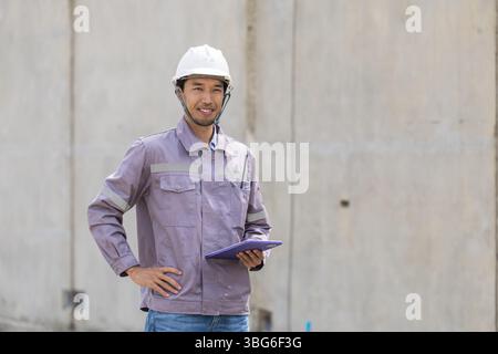 Ritratto ingegnere edile asiatico professionista, lavoratore edile giapponese maschio che lavora nel cantiere edile. Foto Stock